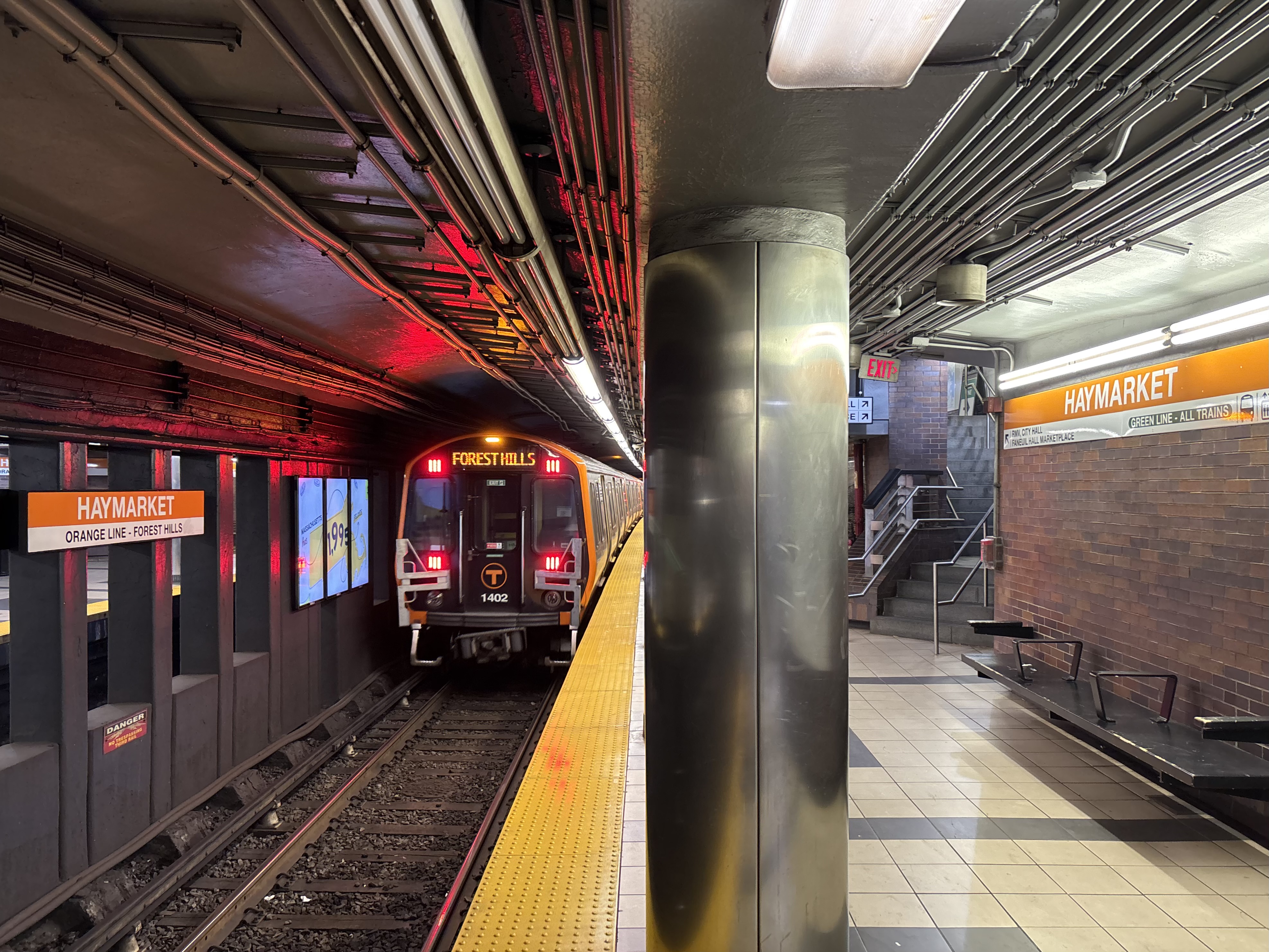 An MBTA Orange Line train leaves Haymarket station beside an empty platform.