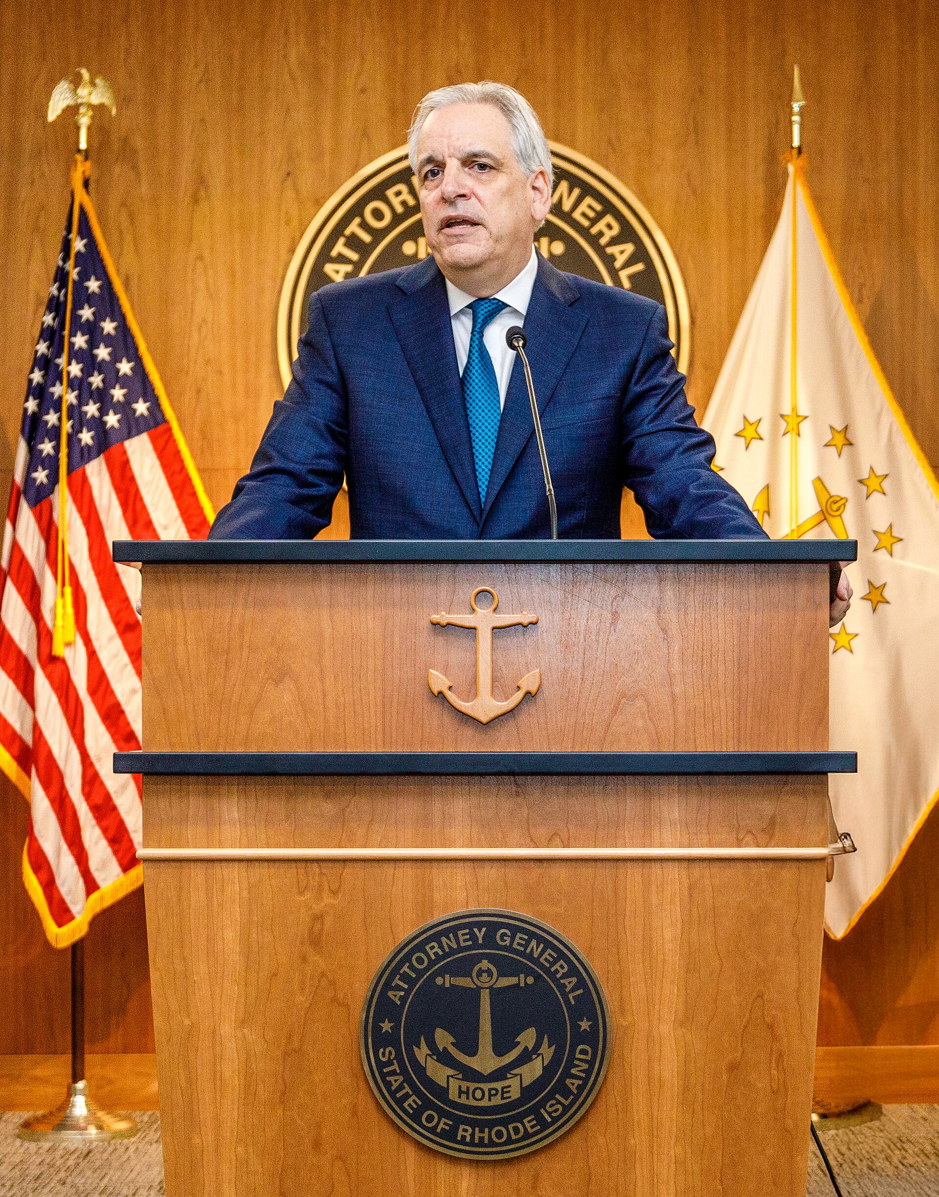 Rhode Island Attorney General Peter Neronha speaks at a lectern.