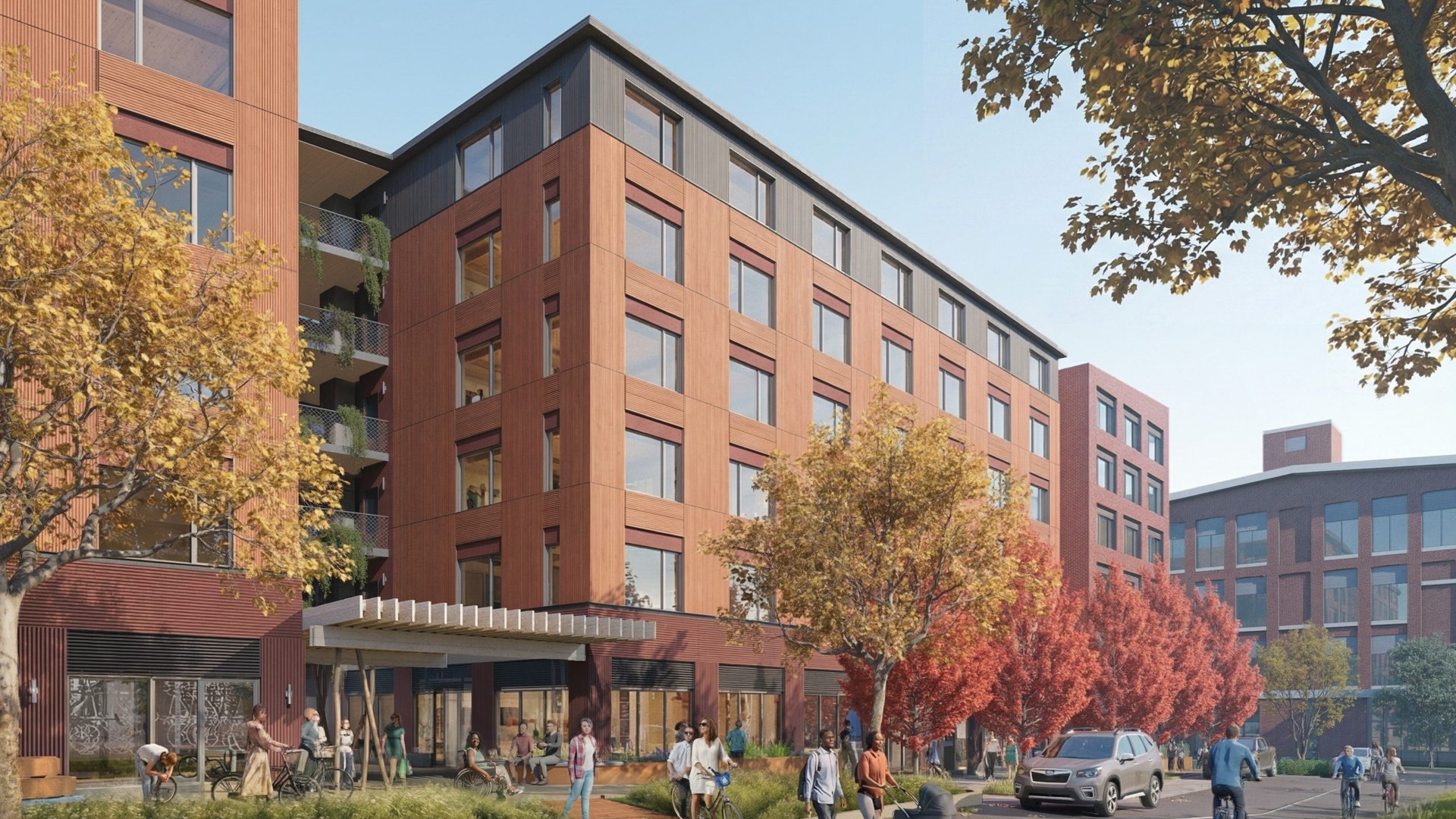 A rendering of a brick and wood mid-rise apartment building on a street with autumn trees, cyclists, and a lake behind it.