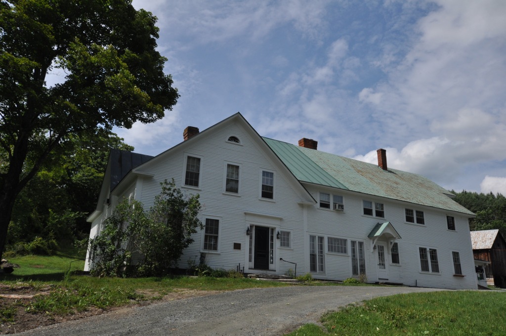 A white farmhouse with a green roof at King Farm in Woodstock, Vermont.