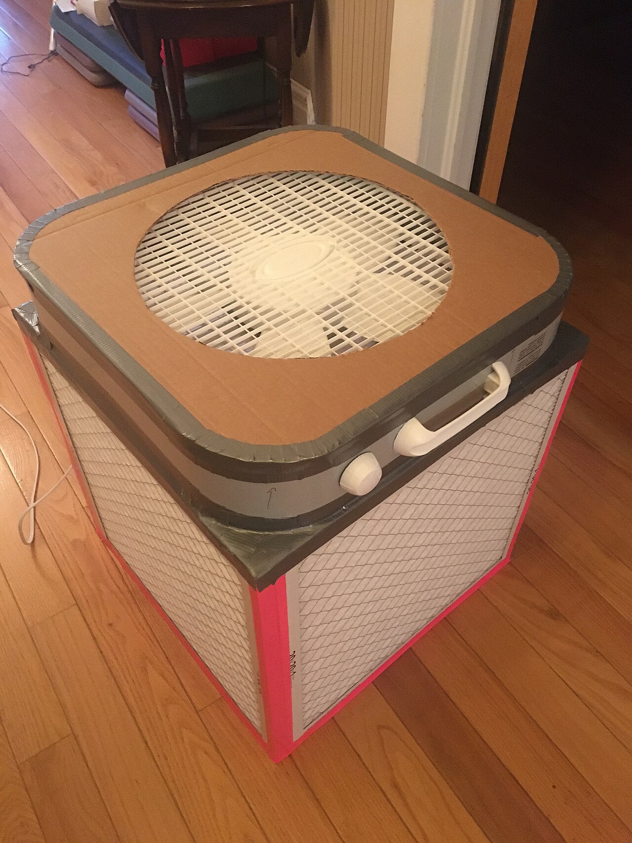 A box fan mounted on a cube of air filters forming a Corsi-Rosenthal box.