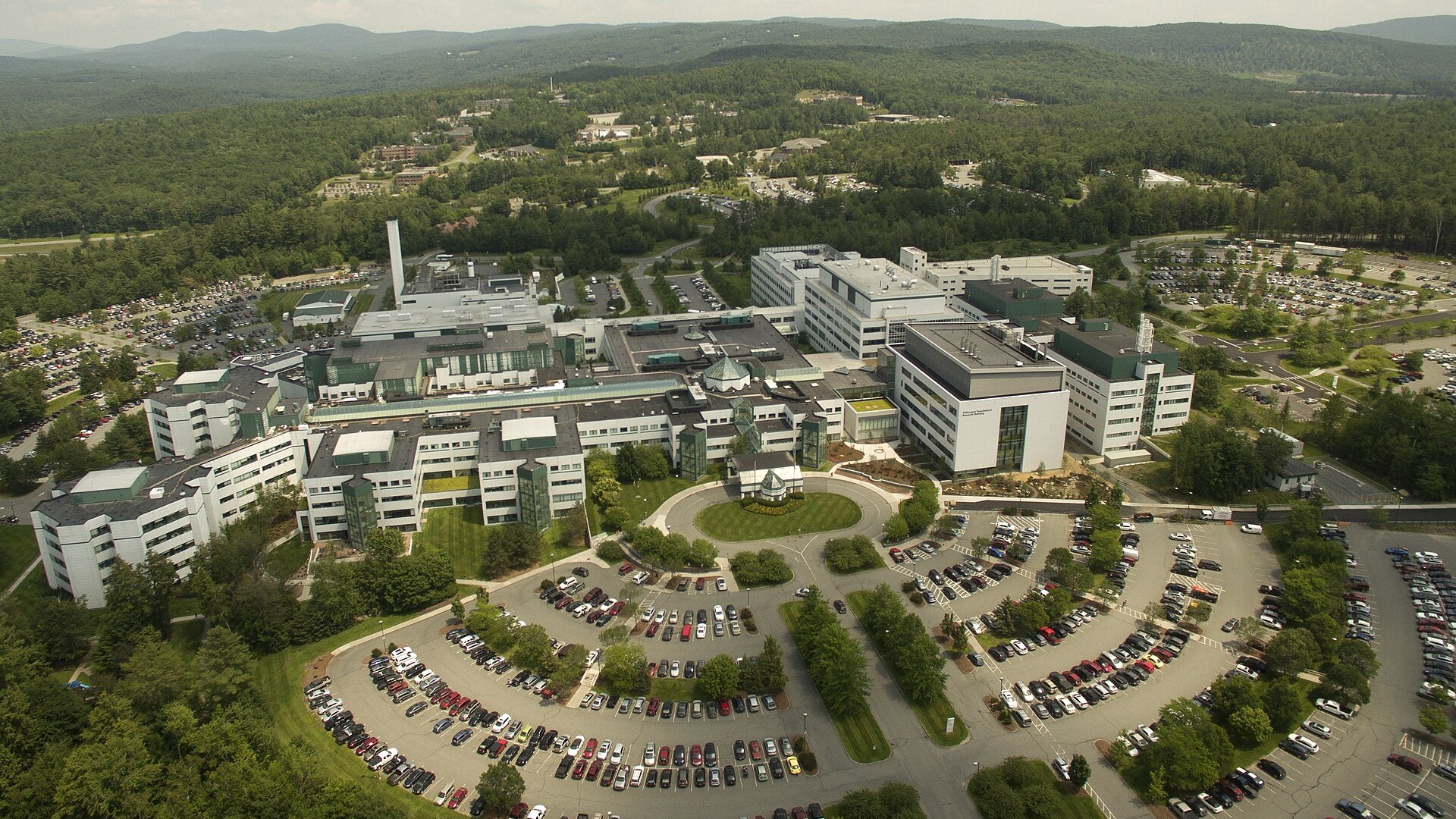 An aerial view of the Dartmouth Hitchcock Medical Center campus in Lebanon, with white hospital buildings and curved parking lots.