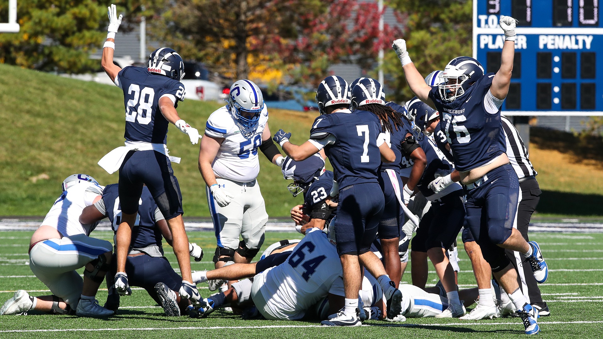 Middlebury football players celebrate around a teammate holding the ball during the Colby game.