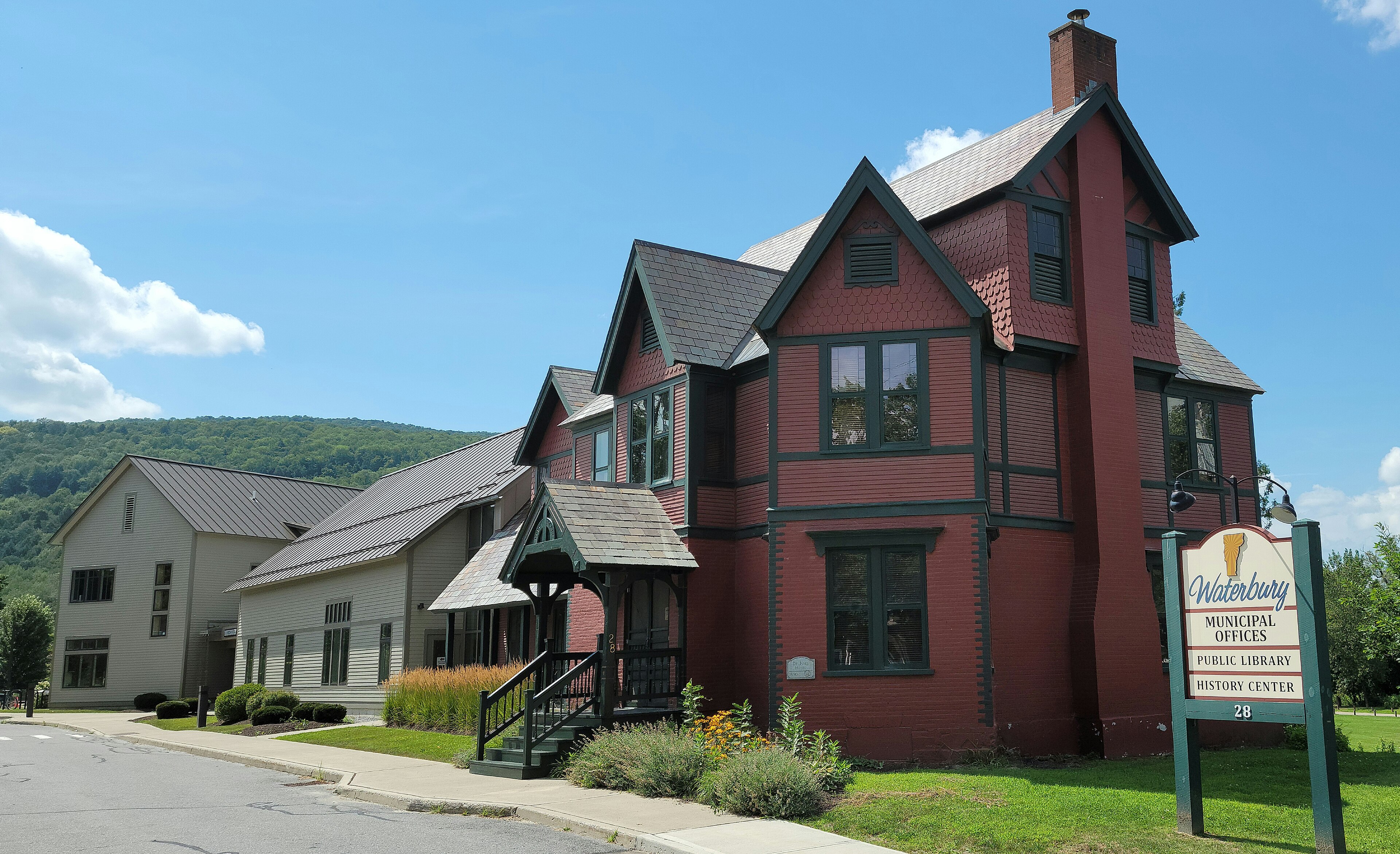 The municipal office building and library in Waterbury, Vermont, beside a lawn and trees.