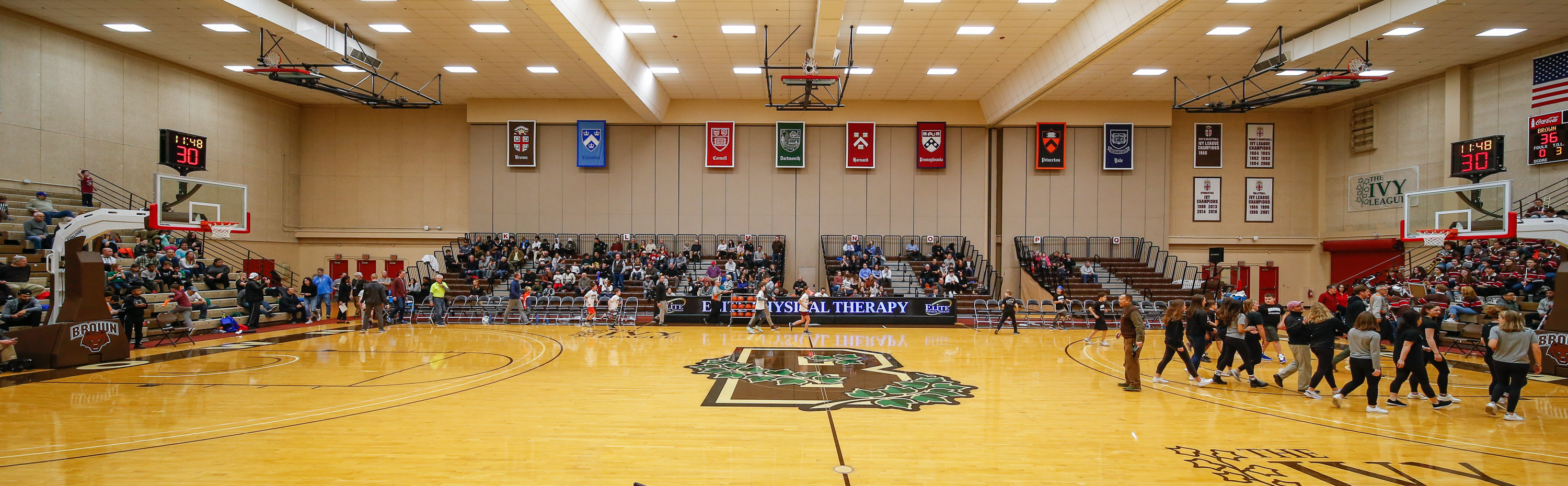 Brown University's basketball court with spectators and Ivy League banners in the Pizzitola Sports Center.