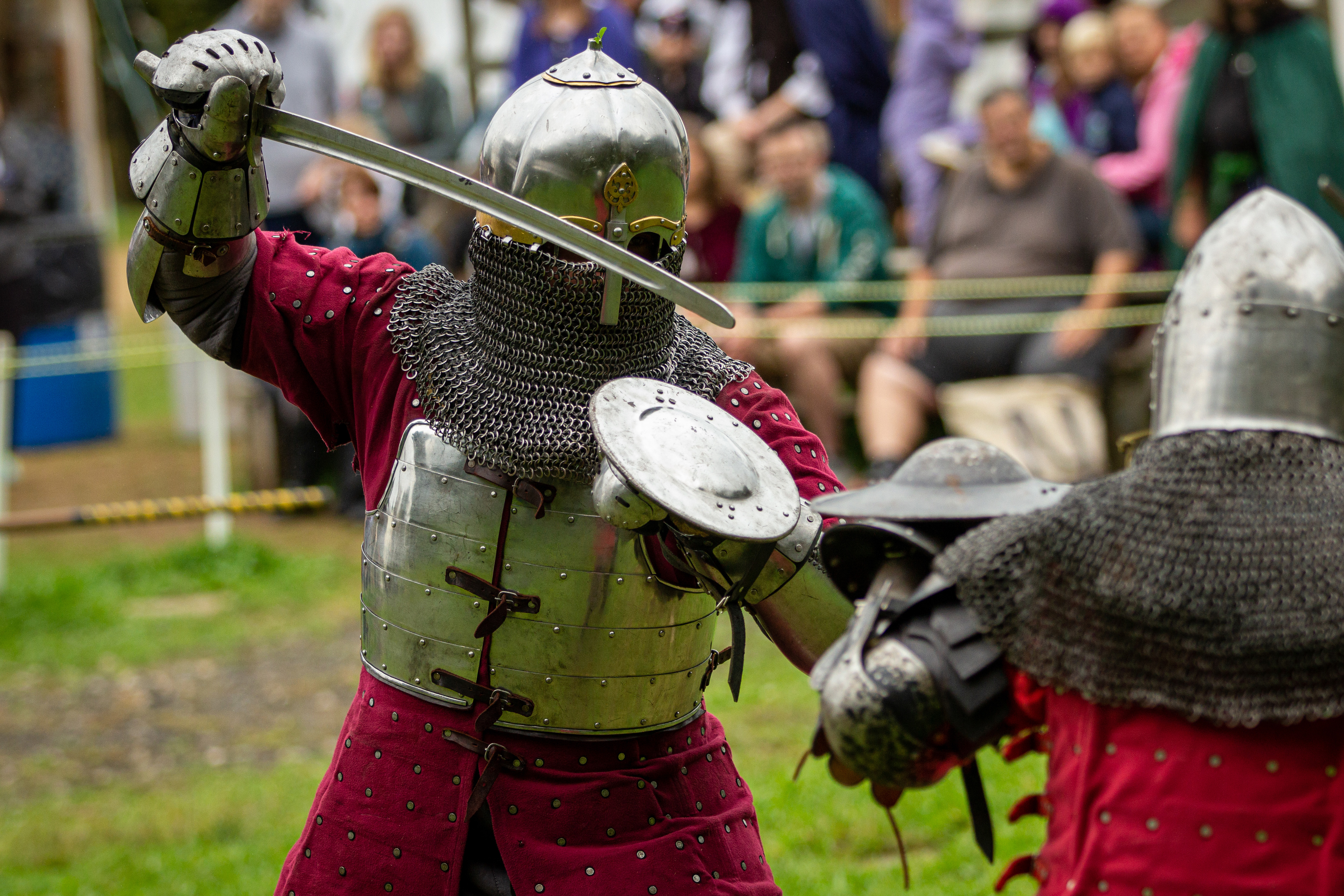 Armored knights with shields face each other on the Faire battlefield.
