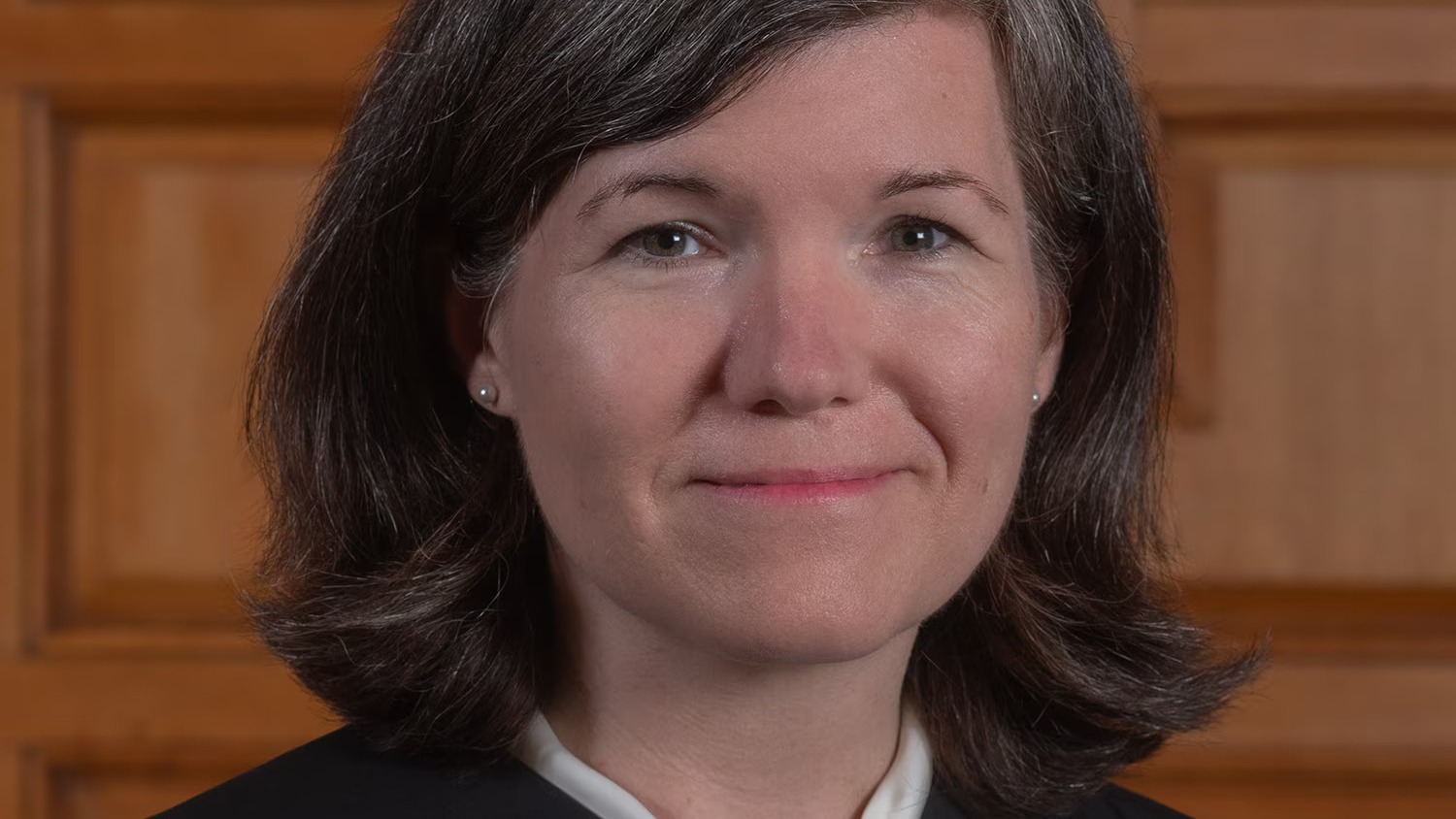 Justice Elizabeth N. Dewar in a black judicial robe against wood paneling.