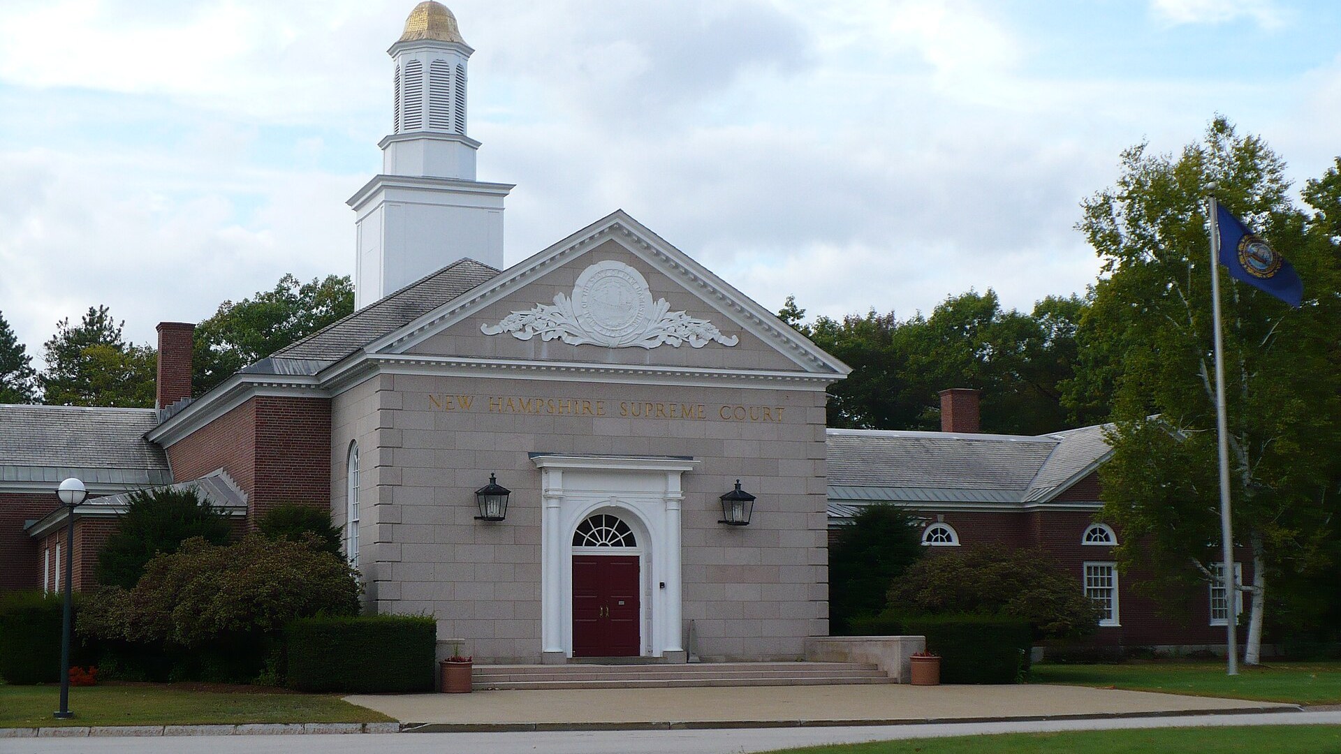 The stone front of the New Hampshire Supreme Court, with gold letters over a red door and a white cupola.