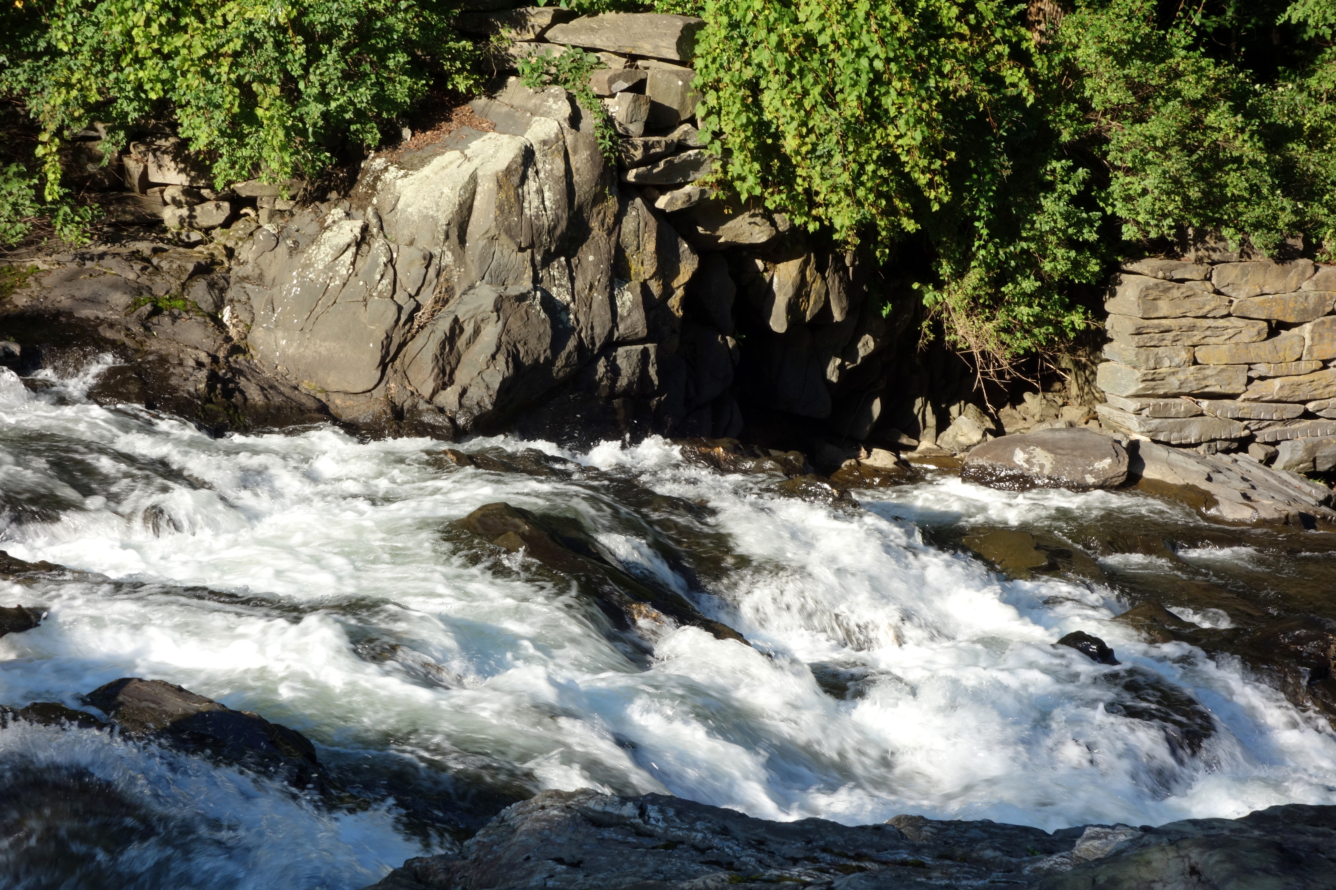 Whitewater flows past rocks and trees along the Ompompanoosuc River in Thetford Center, Vermont.
